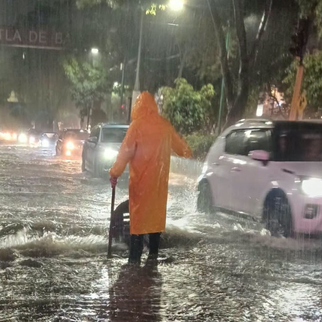 Un elementos de Protección Civil de Tlalnepantla intenta drenar una inundación