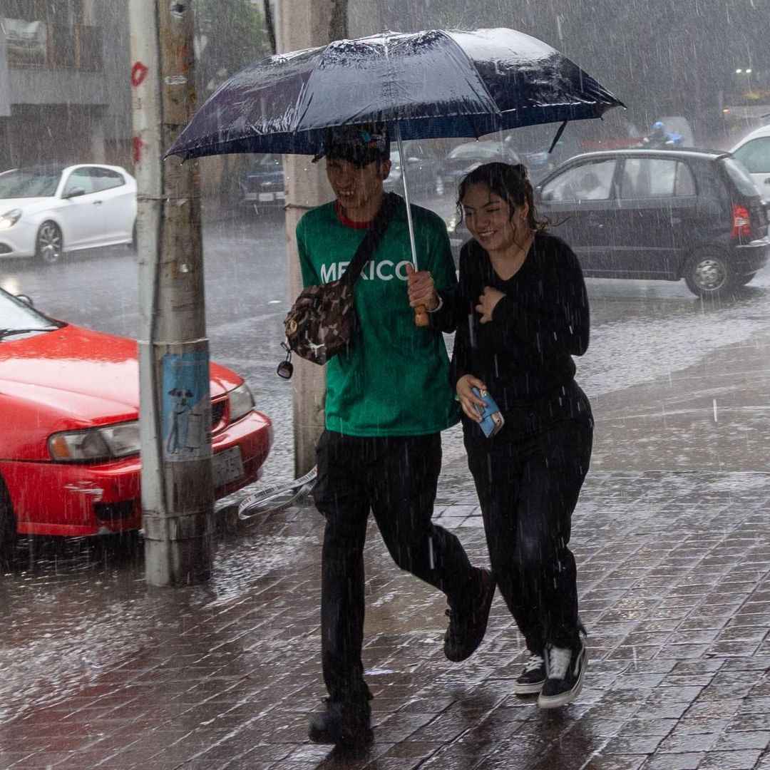 Dos jóvenes intentan protegerse de la lluvia en la CDMX