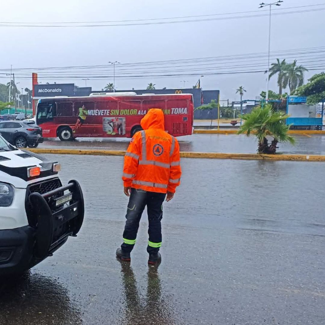 Un elemento de Protección Civil de Acapulco vigila el tránsito tras las fuertes lluvias en el puerto