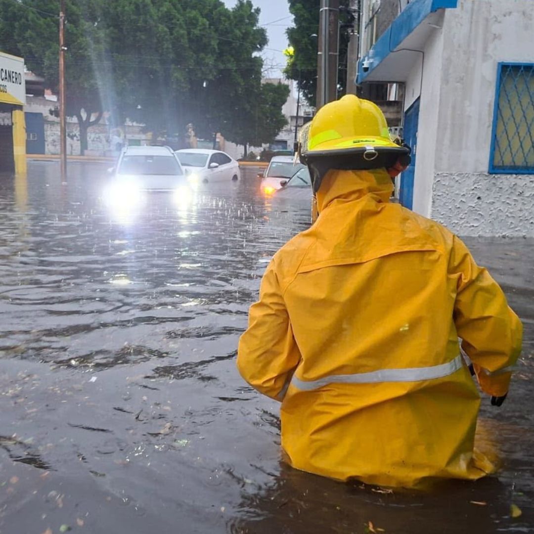 Un elemento de Protección Civil ayuda a ciudadanos durante inundación en Puebla