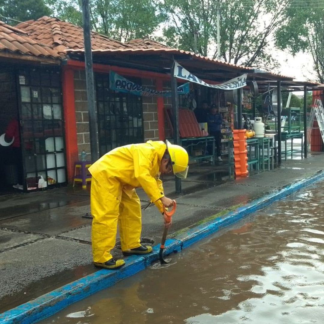 Un bombero intenta desazolvar una alcantarilla en una calle inundada