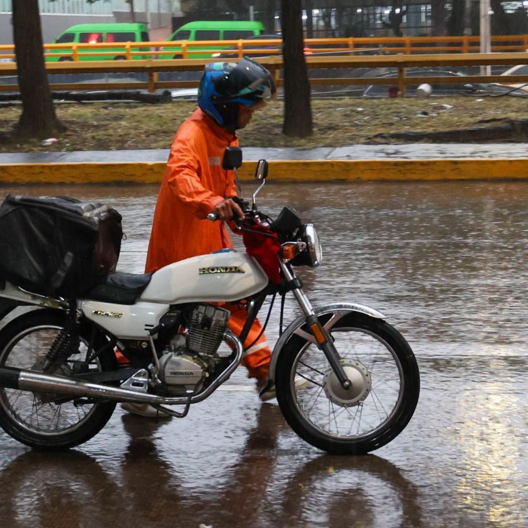 Un motociclista camina con su vehículo averiado en la CDMX