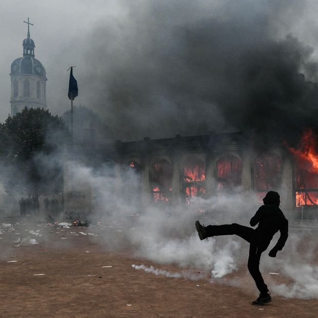 Un manifestante patea un proyectil mientras permanece en medio de gases lacrimógenos frente a la oficina de turismo de Lyon