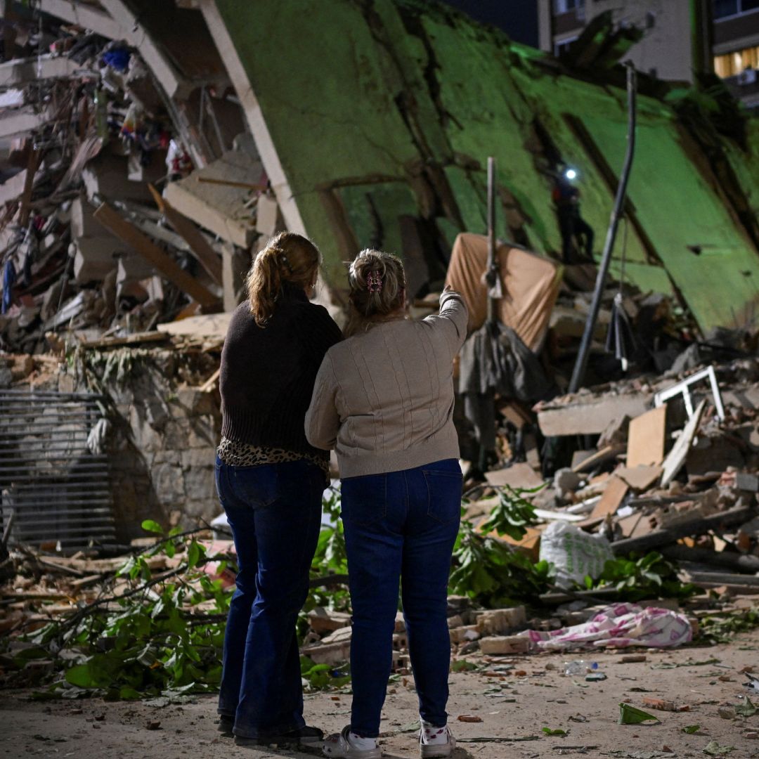 Venezolanas esperan en el lugar de un edificio derrumbado mientras los equipos de emergencia buscan a sus familiares.